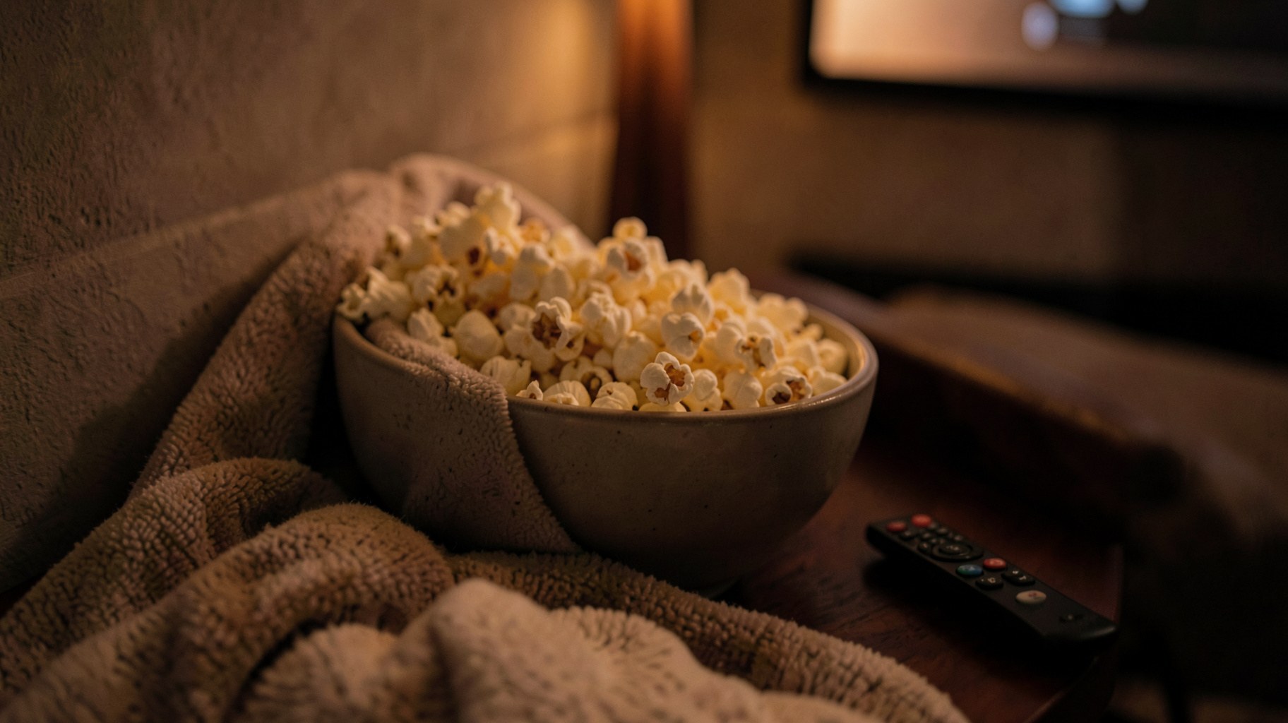 ポップコーンとブランケットが置かれたリビングでの映画鑑賞の雰囲気